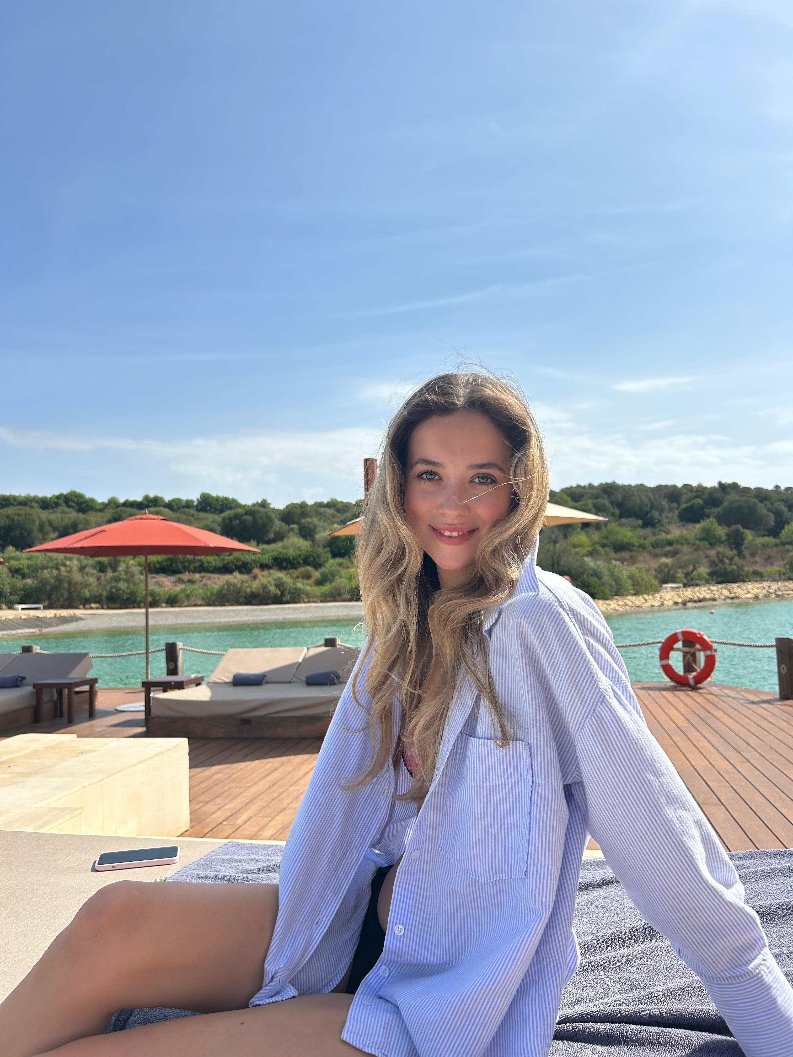 Tess, founder of Bijou Travel, smiling by the water at a seaside resort